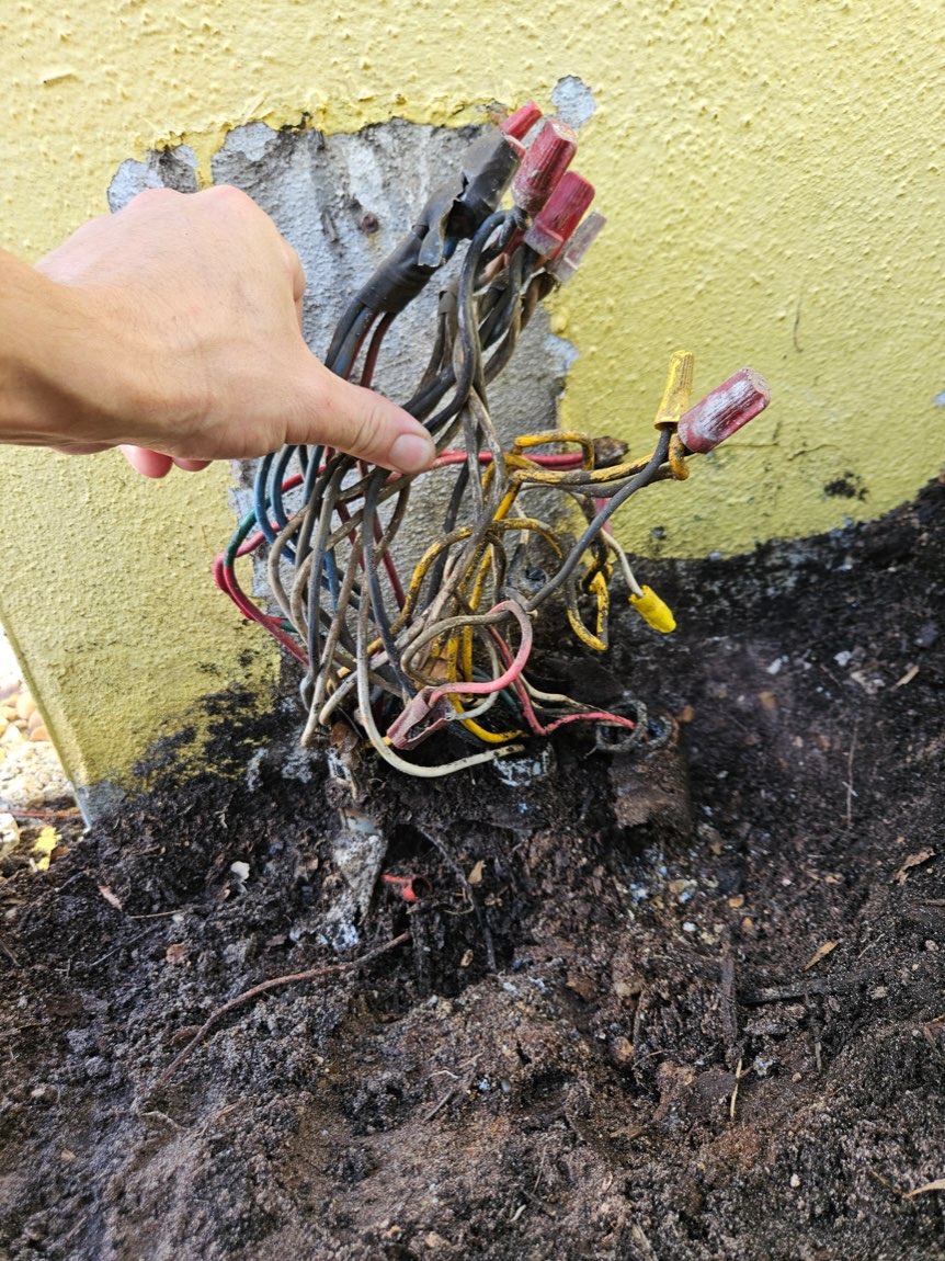 Burned, exposed wiring bundle at the base of a wall before repair