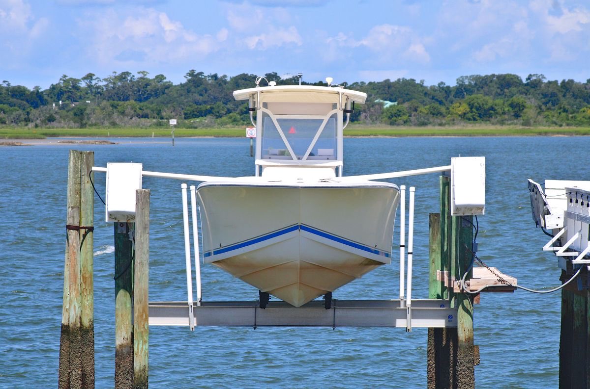 A boat raised on a canal-front boat lift over the water
